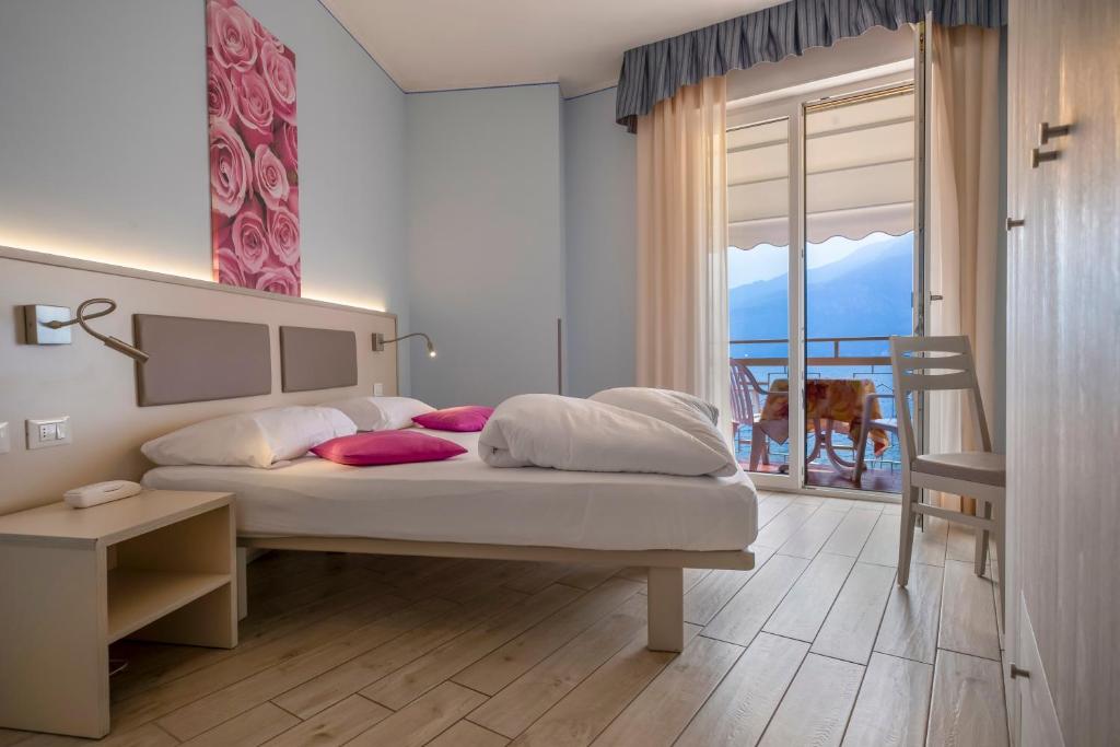une chambre avec un grand lit et un balcon dans l'établissement Hotel Firenze 3 Stelle Superior, à Brenzone