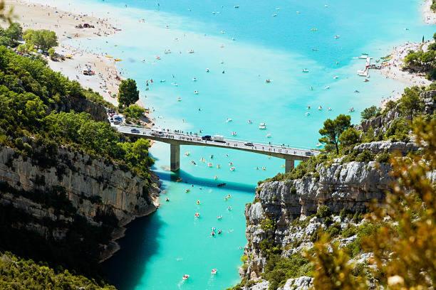 un pont sur une masse d'eau avec un groupe de gens dans l'établissement Camping 3etoiles Lac DE STE CROIX GORGES DU VERDON MOUSTIERS STE MARIE ACTVITES NAUTIQUES RANDONNEES, à Sainte-Croix-de-Verdon