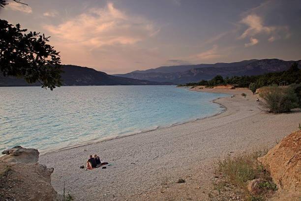 un groupe de personnes se posant sur une plage au bord de l'eau dans l'établissement Camping 3etoiles Lac DE STE CROIX GORGES DU VERDON MOUSTIERS STE MARIE ACTVITES NAUTIQUES RANDONNEES, à Sainte-Croix-de-Verdon