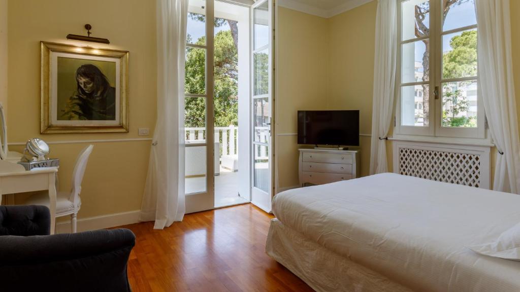 une chambre avec un lit, un bureau et une télévision dans l'établissement Villa Guidi 10 Emma Villas, à Milano Marittima 79 autres photos