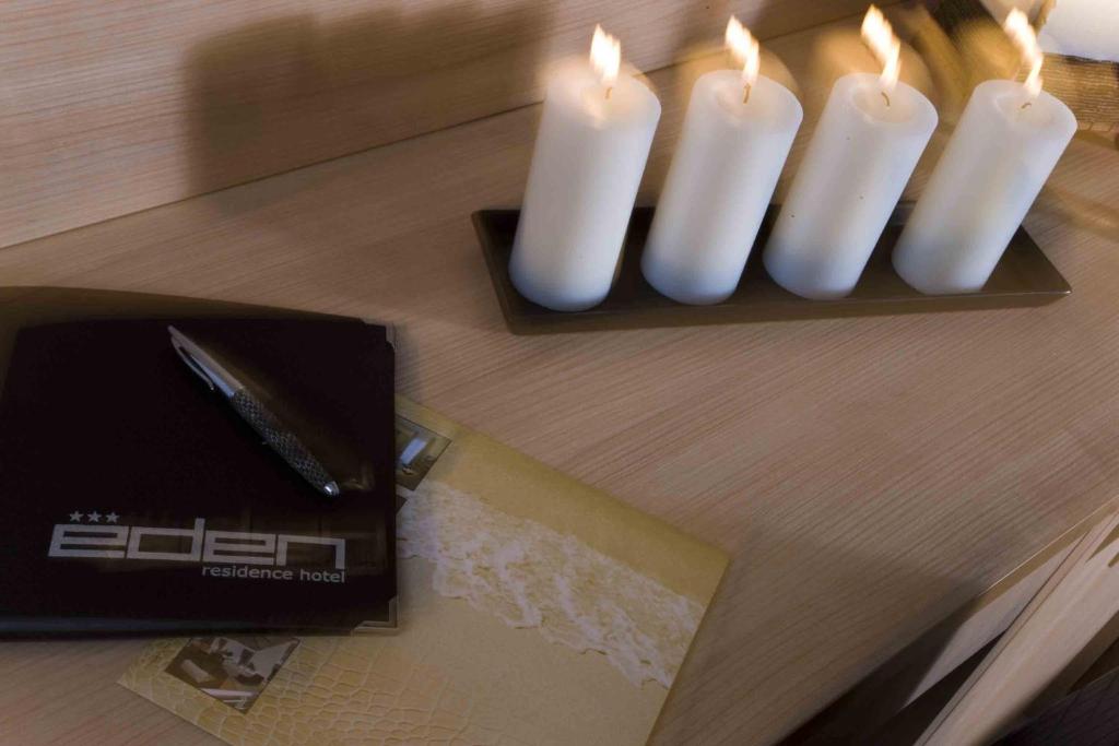 deux bougies blanches assises sur une table à côté d'une échelle dans l'établissement Residence Eden & Spa, à Gabicce Mare