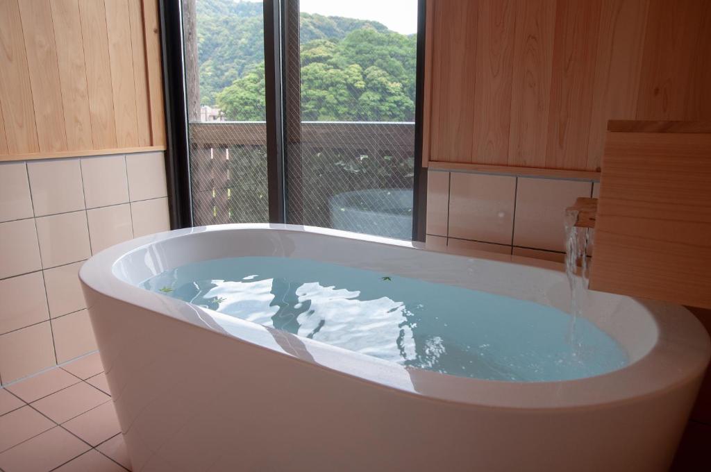 une baignoire dans une salle de bain avec une fenêtre dans l'établissement Kirishima miyama hotel, à Kirishima