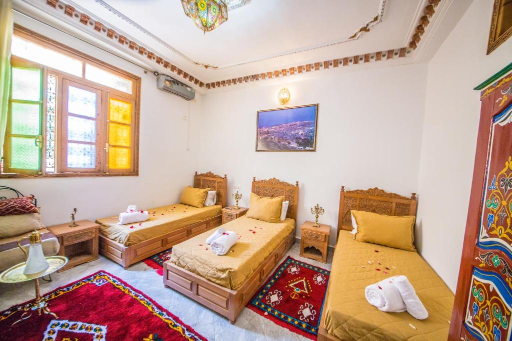 Cette chambre comprend 3 lits et un tapis. dans l'établissement Riad Mahrez, à Fès