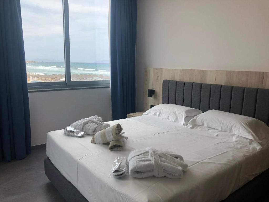 - une chambre dotée d'un lit avec des serviettes et des chaussures dans l'établissement Baia dei Mulini Resort & Spa, à Trapani