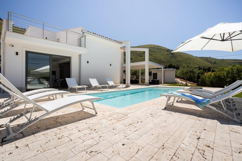Cette villa dispose d'une piscine avec des chaises et un parasol. dans l'établissement Grande Villa privata con piscina a Scopello, à Castellammare del Golfo