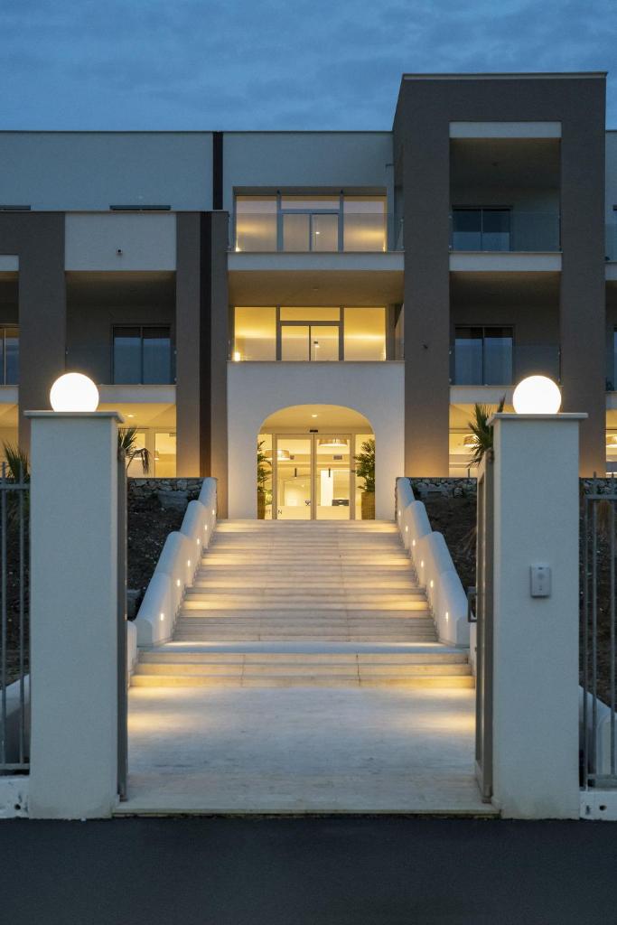 un bâtiment avec un escalier devant lui dans l'établissement Resort La Battigia Beach & Spa, à Alcamo Marina