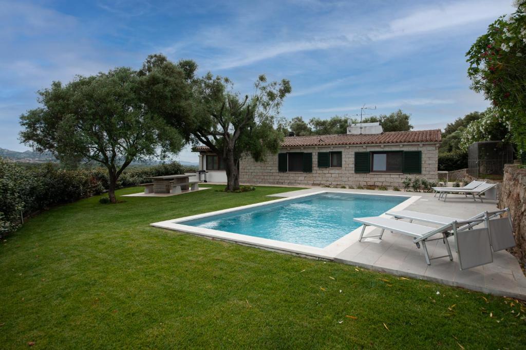 une cour arrière avec une piscine et une maison dans l'établissement [VILLA CON PISCINA] NELLE COLLINE DELLA GALLURA, à Arzachena