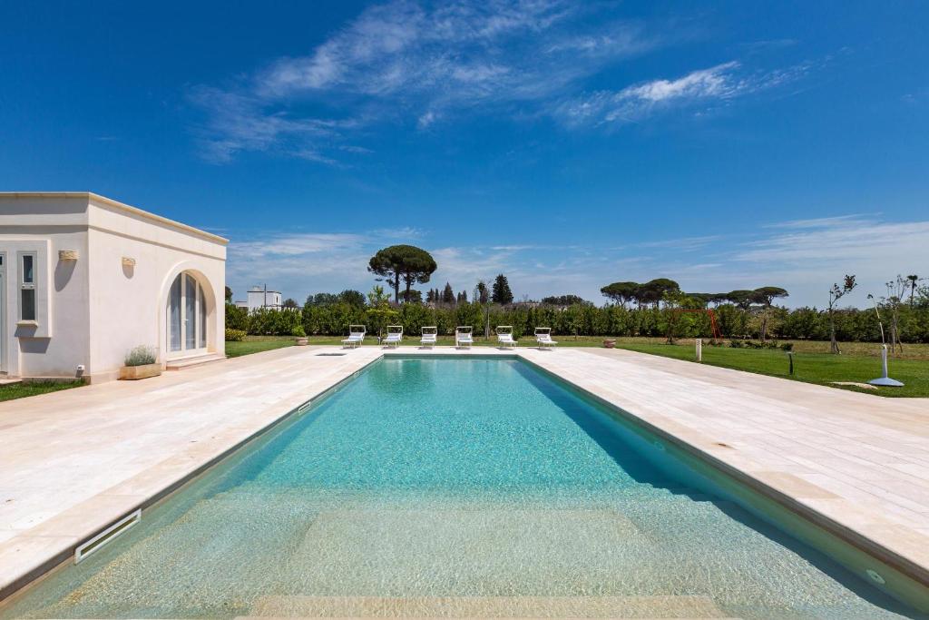 une piscine dans une cour avec des chaises et un ciel dans l'établissement Villa Donna Sofia by Perle di Puglia, à Alezio