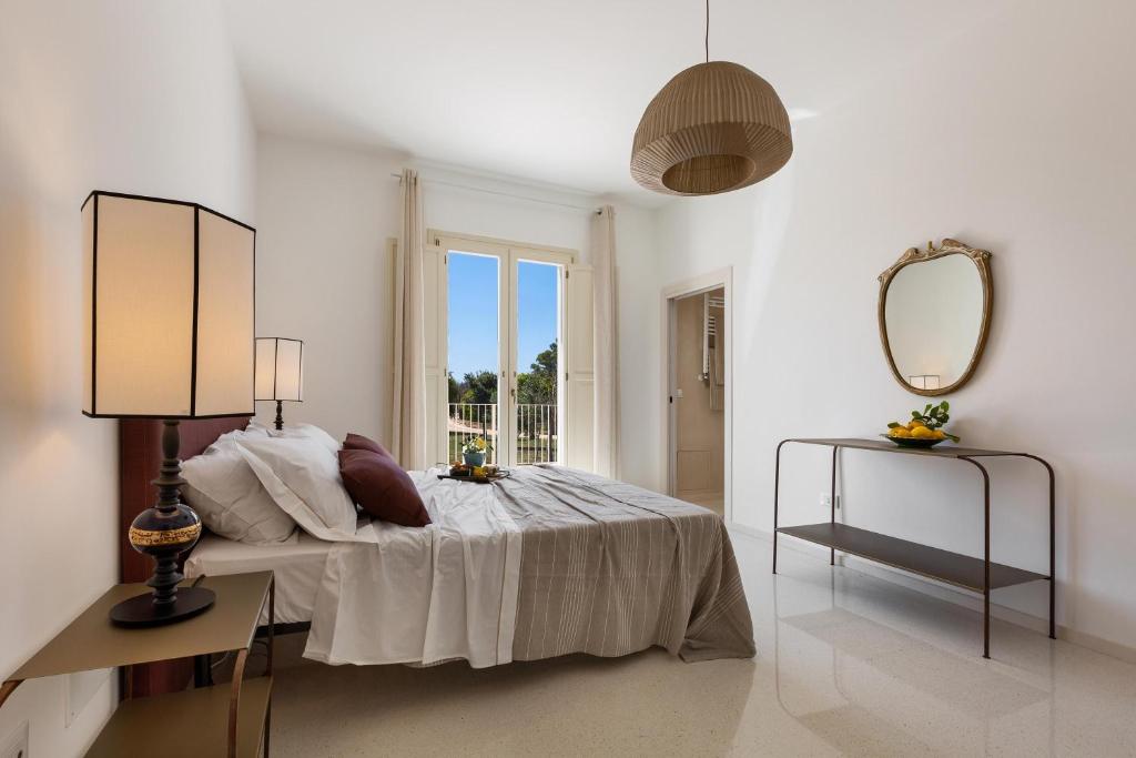 une chambre blanche avec un lit et un miroir dans l'établissement Villa Donna Sofia by Perle di Puglia, à Alezio