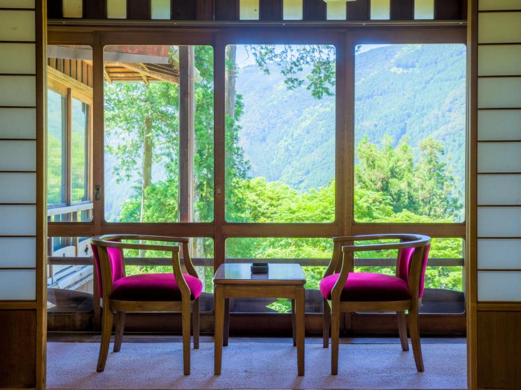 deux chaises et une table devant une fenêtre dans l'établissement Yunoshimakan, à Gero