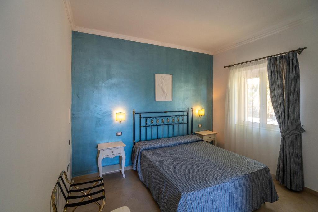 une chambre avec un lit et un mur bleu dans l'établissement Hotel Boutique Il Castellino Relais, à Vieste