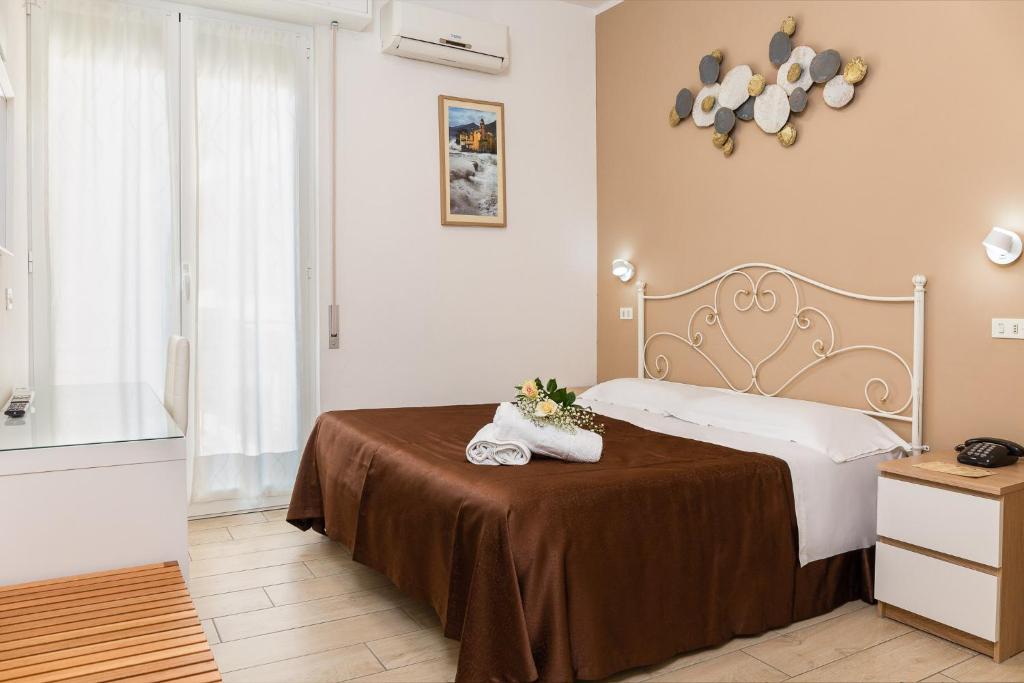 une chambre avec un lit avec deux chaussures sur une table dans l'établissement Hotel Villa Lina, à Loano