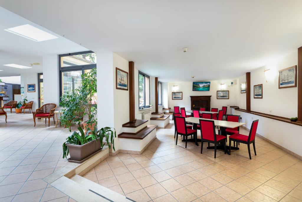 une salle d'attente avec des chaises et des tables rouges dans un hôpital dans l'établissement Hotel Villa Lina, à Loano