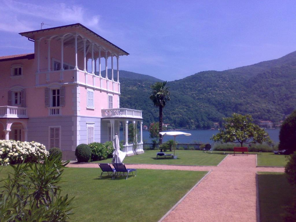 un grand bâtiment avec une pelouse en face d'un lac dans l'établissement Residence Ville Lago Lugano, à Porto Ceresio
