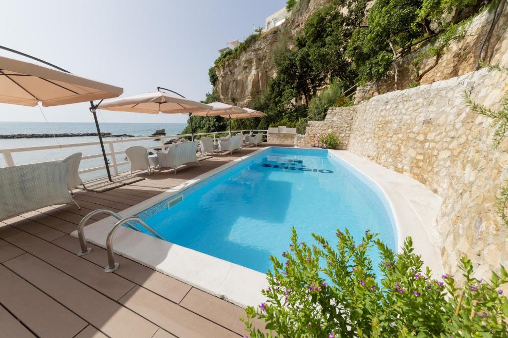 une piscine avec chaises et parasols au bord de l'océan dans l'établissement Hotel Seggio, à Vieste