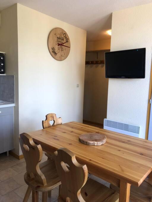 une table en bois dans une cuisine avec une horloge murale dans l'établissement Appartement aux pieds des pistes - La Plagne Montalbert - Panorama 1350, à Aime La Plagne
