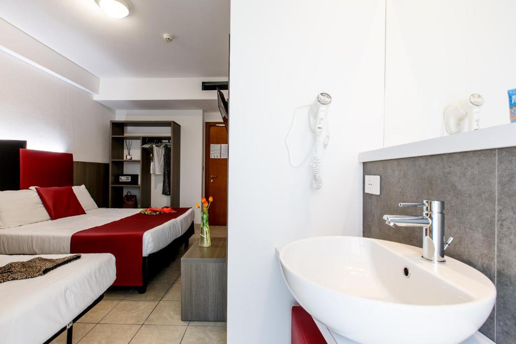 une salle de bain avec un lavabo et une chambre avec un lit dans l'établissement Hotel Grazia Riccione, à Riccione