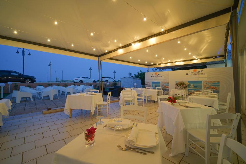 un restaurant avec des tables, des chaises et des lumières blanches dans l'établissement Hotel Rivabella, à Davoli