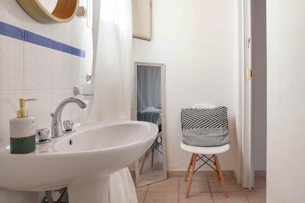 une salle de bain blanche avec un lavabo et une chaise dans l'établissement Villa Marzallo by Villa Plus, à Santa Maria Del Focallo