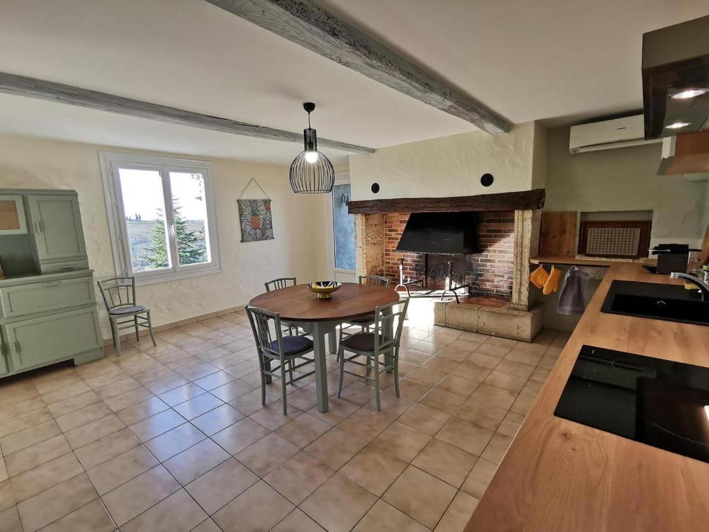 Il comprend une cuisine et une salle à manger avec une table et une cheminée. dans l'établissement Gîte - Le Moussat, à Lagraulet-du-Gers