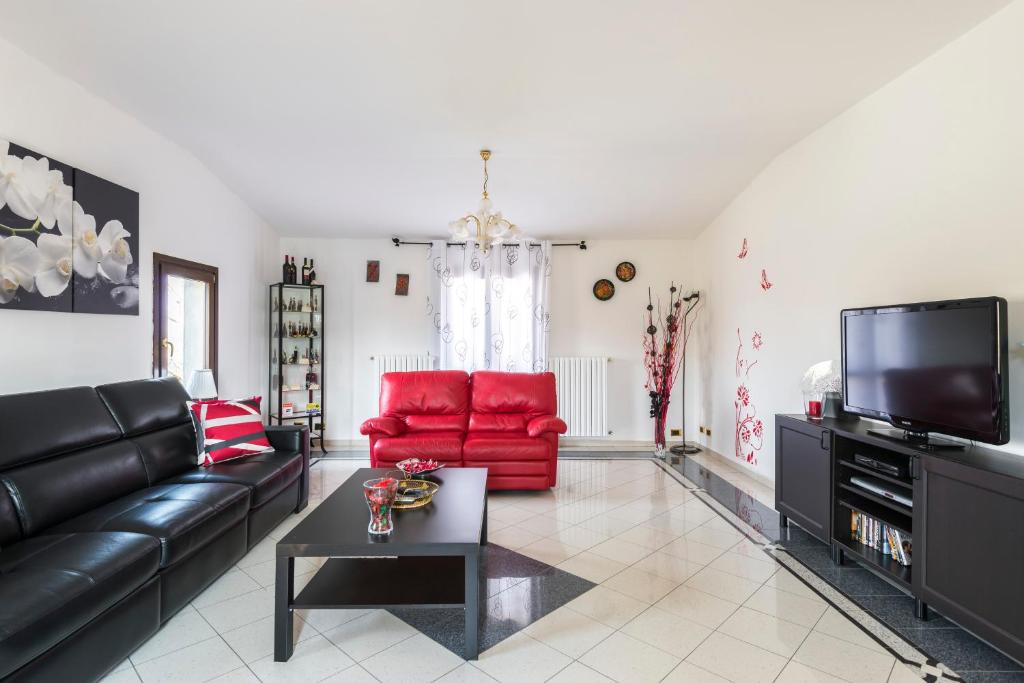 un salon avec un canapé en cuir noir et des chaises rouges dans l'établissement Casa delle Noci country house, pool & SPA, à Modène
