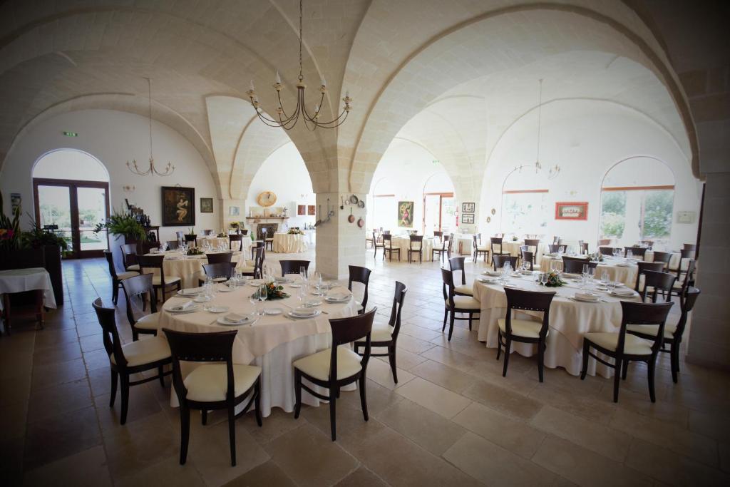 une salle à manger avec des tables et des chaises blanches dans l'établissement Casale del Murgese Country Resort, à Savelletri di Fasano