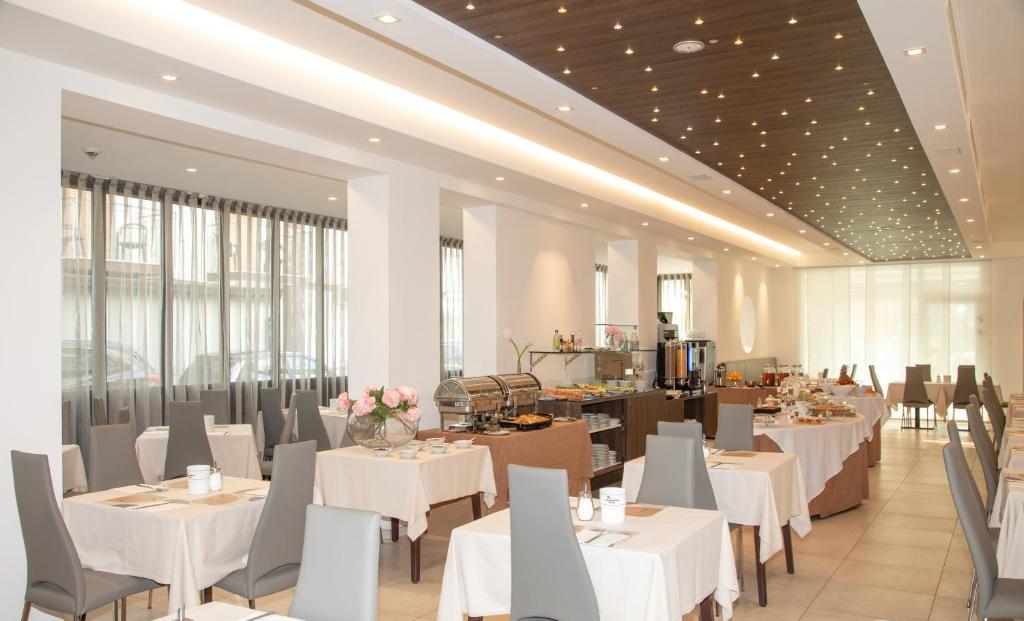 un restaurant avec des tables et des chaises blanches et des fenêtres dans l'établissement Hotel & Aparthotel Carinthia S, à Lido di Jesolo