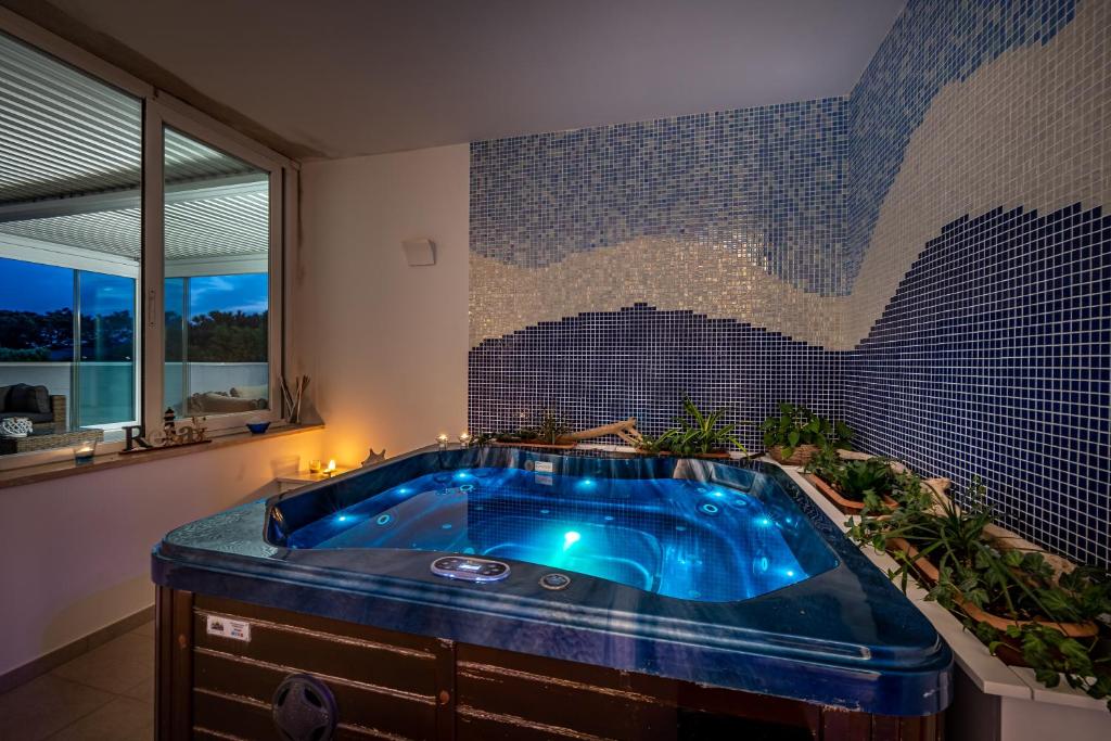 La salle de bains est pourvue d'une baignoire bleue et d'un mur en mosaïque. dans l'établissement Mareblù - Tuscany Green Aparthotel, à Principina a Mare