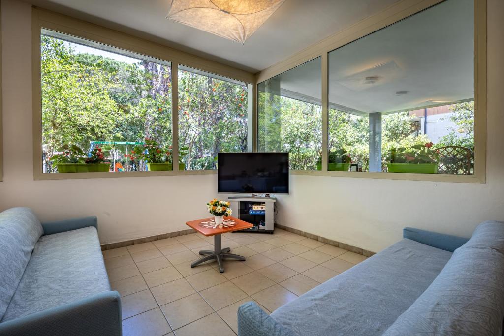 - un salon avec deux canapés bleus et une télévision dans l'établissement Mareblù - Tuscany Green Aparthotel, à Principina a Mare