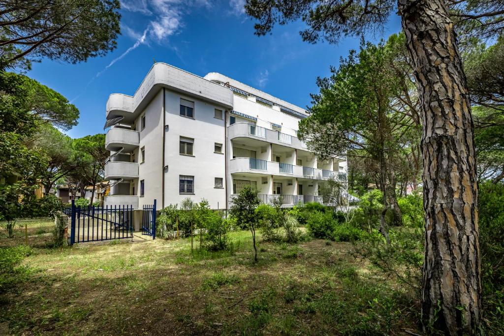 un immeuble d'appartements dans un parc avec un arbre dans l'établissement Mareblù - Tuscany Green Aparthotel, à Principina a Mare