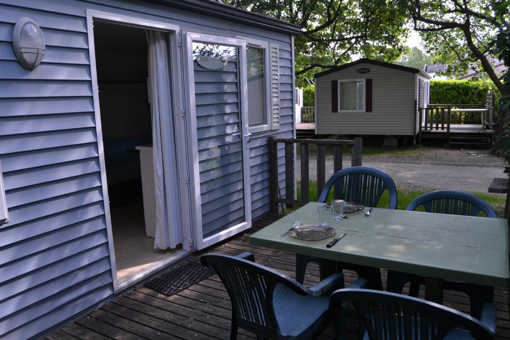 une table et des chaises sur une terrasse avec une porte ouverte dans l'établissement Camping maeva Escapades Le Casque Roi, à Salavas
