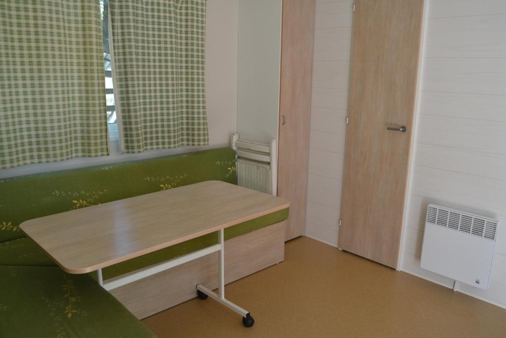 une chambre avec une table et un banc vert dans l'établissement Camping maeva Escapades Le Casque Roi, à Salavas 31 autres photos