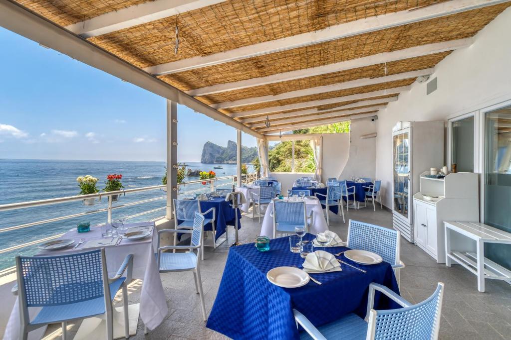 un restaurant avec des tables et des chaises bleues et l'océan dans l'établissement Belmare Residence on the beach, à Nerano