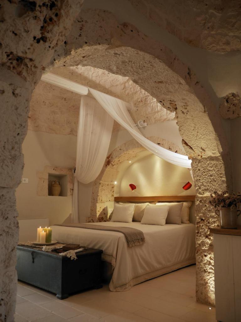 une chambre avec un grand lit dans un mur de pierre dans l'établissement Trulli Terra Viva, à Alberobello