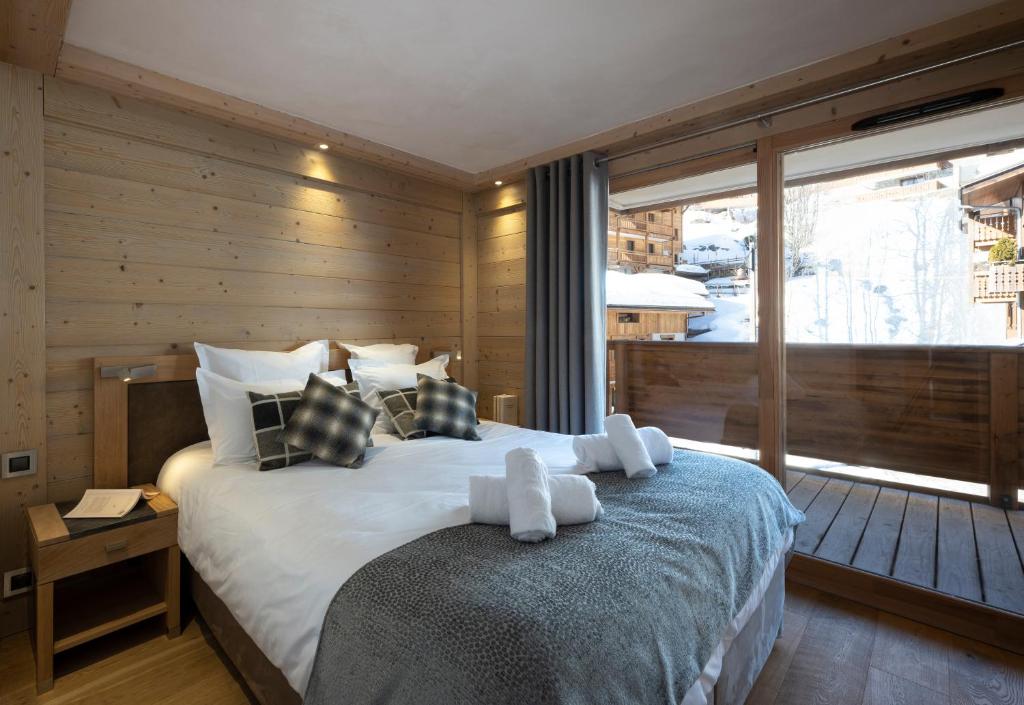 une chambre avec un grand lit et une grande fenêtre dans l'établissement MGM Hôtels & Résidences - Résidence Le Roc Des Tours, au Grand-Bornand