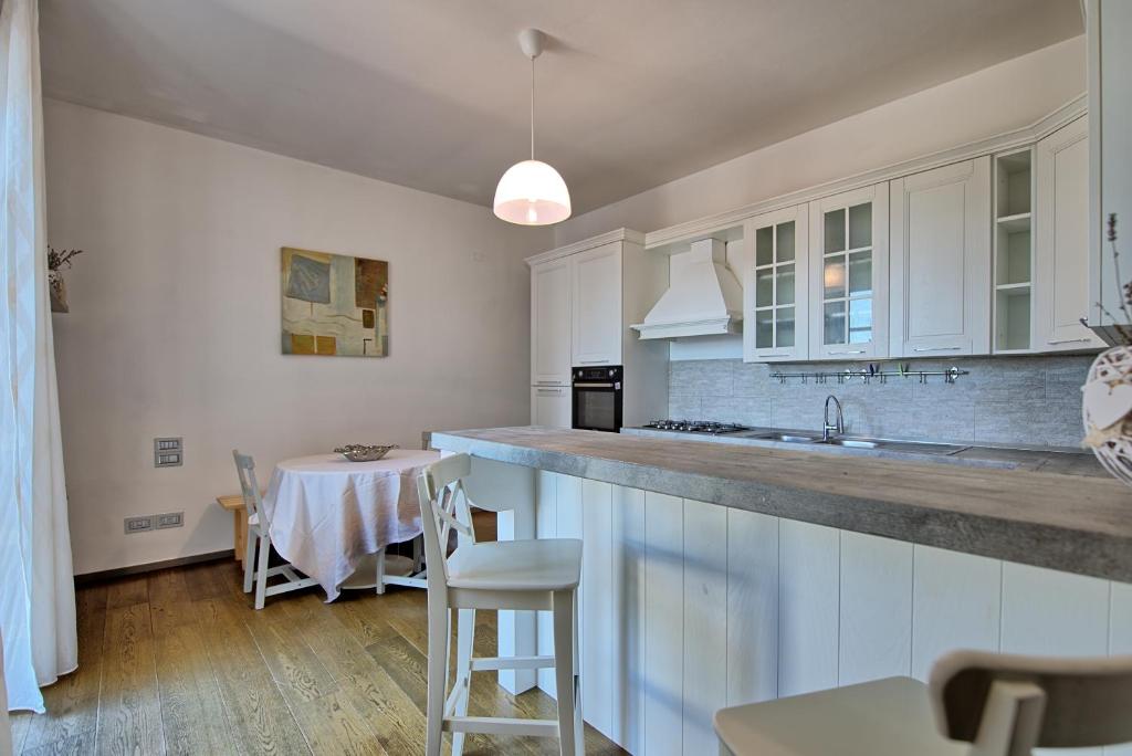 une cuisine avec des placards blancs, une table et un comptoir de cuisine dans l'établissement Casa White by PosarelliVillas, à Castiglion Fiorentino