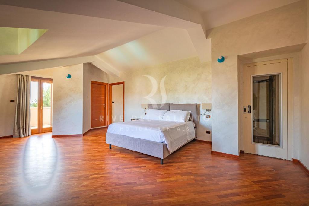 une chambre avec un lit blanc et un parquet dans l'établissement Villa Rapolla by RivedelSalento, à Lecce