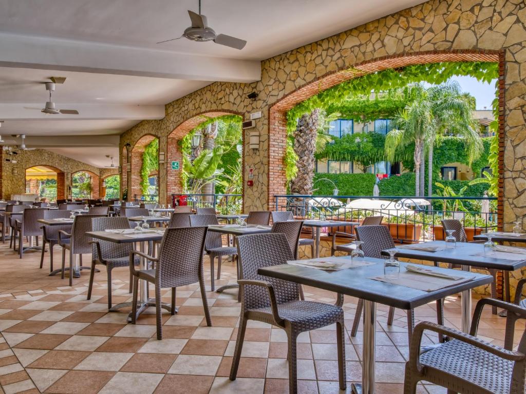 un restaurant avec des tables et des chaises et un mur de pierre dans l'établissement Hotel Caesar Palace, à Giardini Naxos