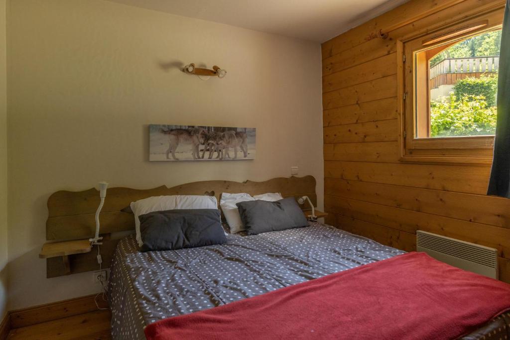- une chambre avec un lit et un mur en bois dans l'établissement Morillon 1100 Skis aux pieds, à Morillon