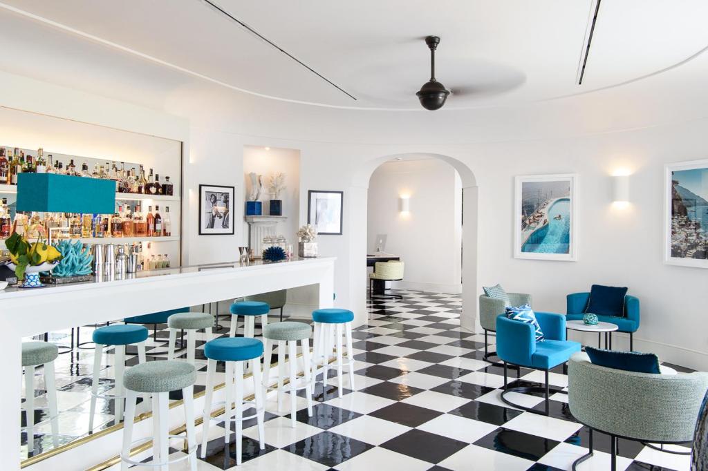 - un bar avec des chaises bleues et un sol en damier dans l'établissement Hotel Miramalfi, à Amalfi