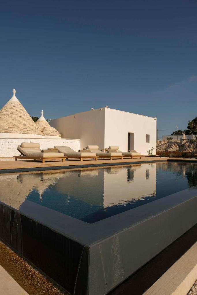 une piscine avec des chaises longues et un bâtiment dans l'établissement Trulli Petramyrta, à Ceglie Messapica