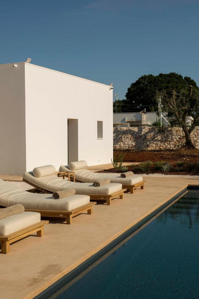 une rangée de chaises longues à côté d'une piscine dans l'établissement Trulli Petramyrta, à Ceglie Messapica