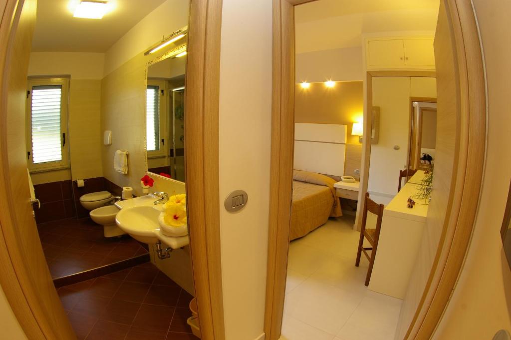 une salle de bain avec un lavabo et des toilettes et un lit dans l'établissement Hotel Villaggio Old River, à Capo Vaticano