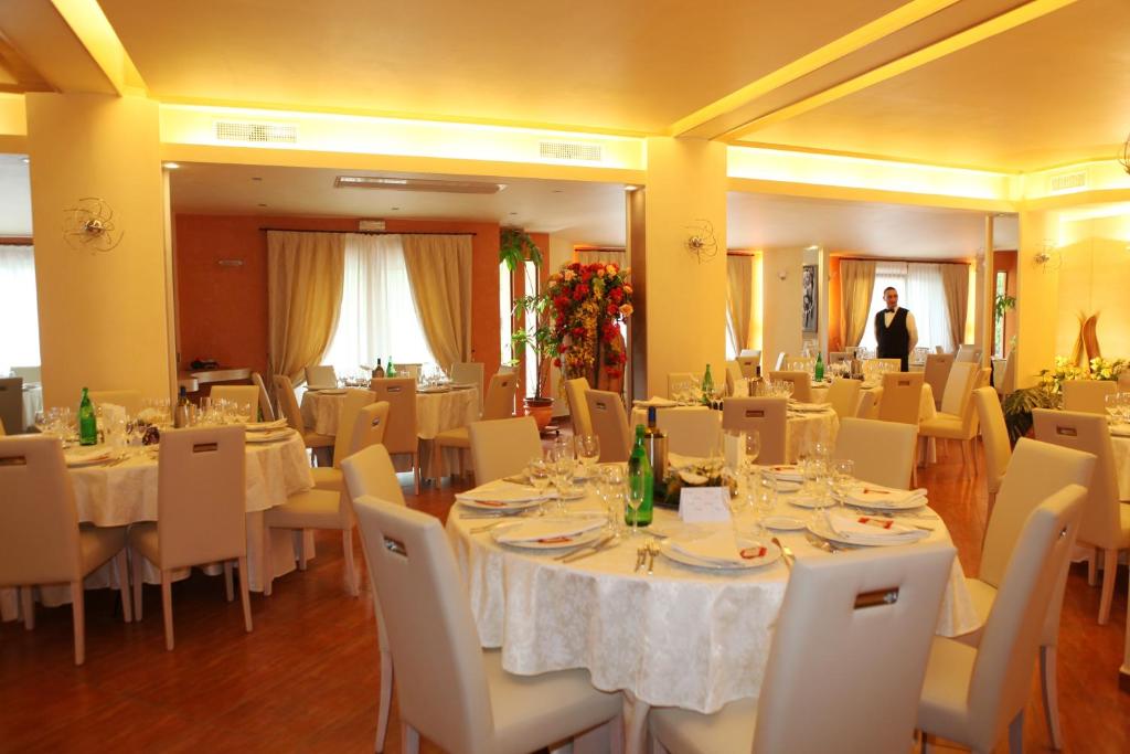 un restaurant avec des tables blanches, des chaises blanches et un homme dans l'établissement Hotel Villaggio Old River, à Capo Vaticano 58 autres photos