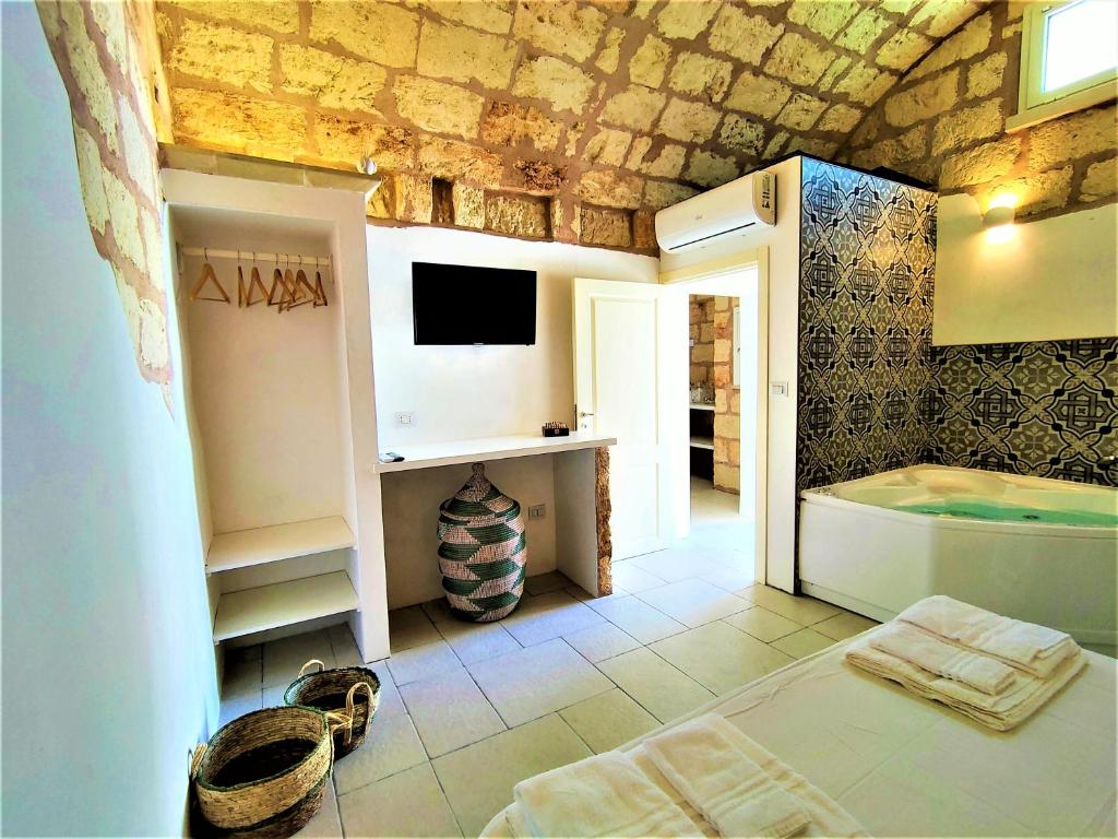 Cette chambre comprend une salle de bains pourvue d'une baignoire et une télévision. dans l'établissement Da Lorenza di Casa Camilla Journey, à Depressa