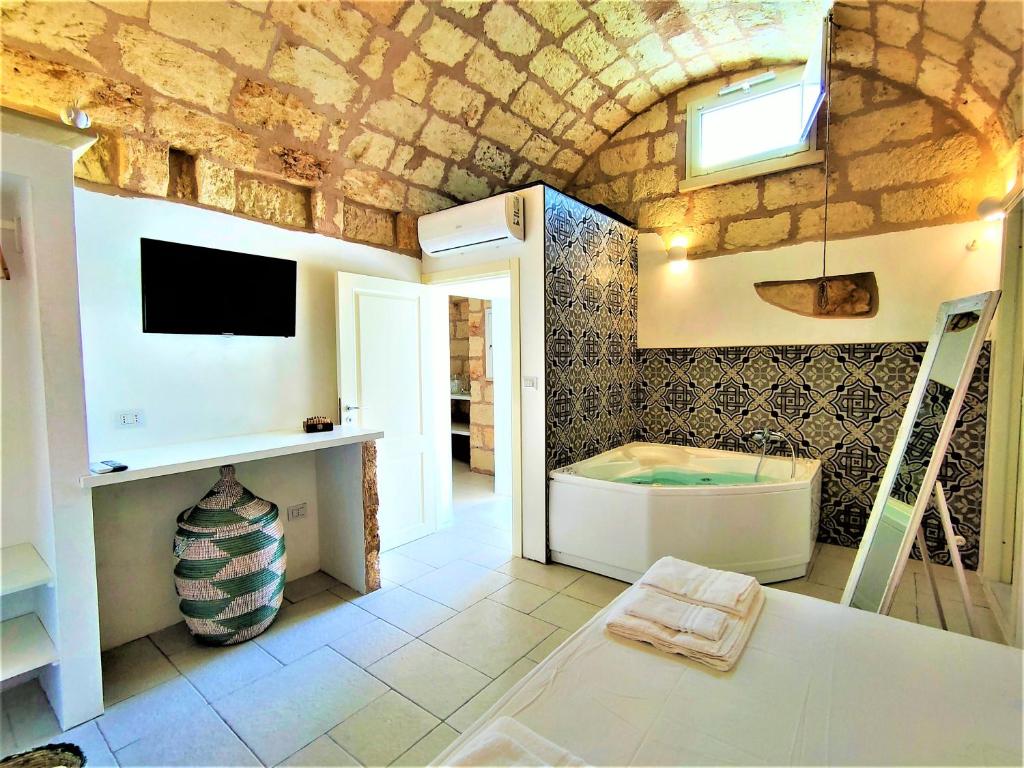 une salle de bain avec une baignoire et une télévision au mur dans l'établissement Da Lorenza di Casa Camilla Journey, à Depressa