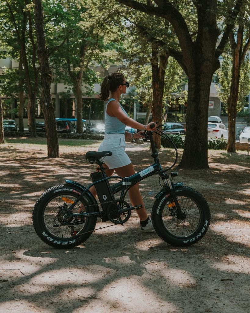Une femme debout à côté d'un vélo dans un parc dans l'établissement Hotel Vienna, à Lignano Sabbiadoro