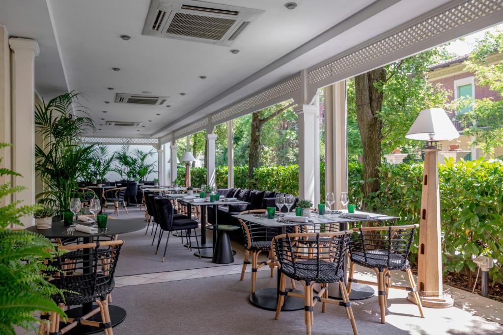 un restaurant avec des tables, des chaises et des fenêtres dans l'établissement Hotel Maestrale, à Riccione