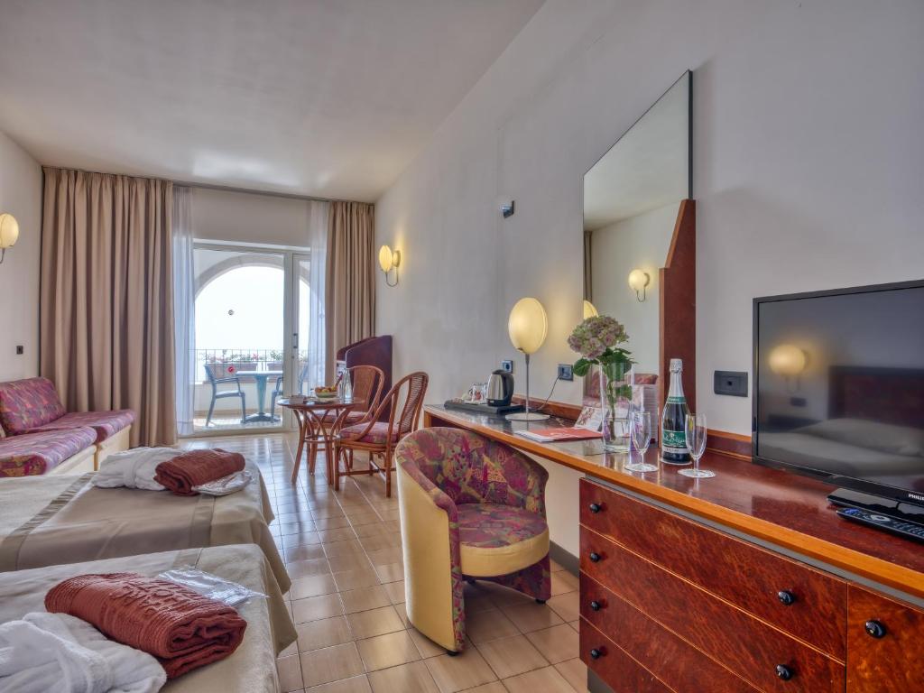 une chambre d'hôtel avec une télévision et un salon dans l'établissement Hotel Olimpo le Terrazze, à Letojanni