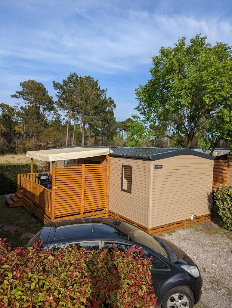 Une petite maison avec une voiture garée devant elle dans l'établissement 200m de la plage Bungalow LUXE de 44m2 Ménage et draps inclus Camping 5 Etoiles Mayotte Lac Biscarrosse Koyobalys, à Biscarrosse